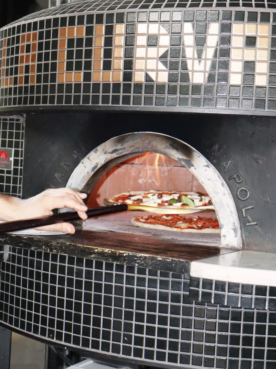 Pizza enfournée dans le four napolitain en mosaïque noire de La Curva, restaurant italien à Villeneuve-d’Ascq