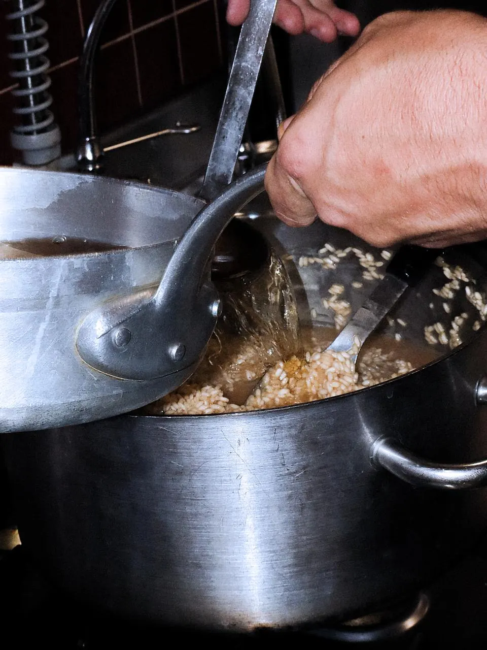 Bouillon versé à la louche sur le riz d’un risotto en cuisson