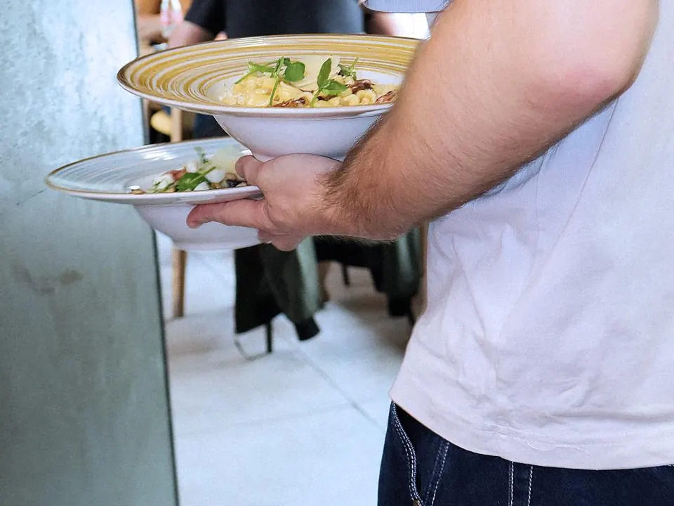 Service en salle : deux assiettes de pâtes portées vers les tables